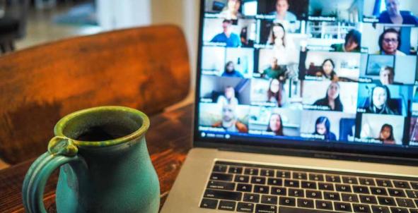 Kop koffie naast een laptop waar een online evenement gaande is