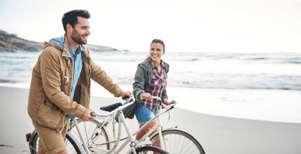 Stel lopend op het strand, fiets aan de hand