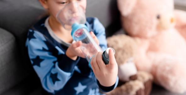 Een jongetje inhaleert medicijnen met een puffer met voorzetkamer