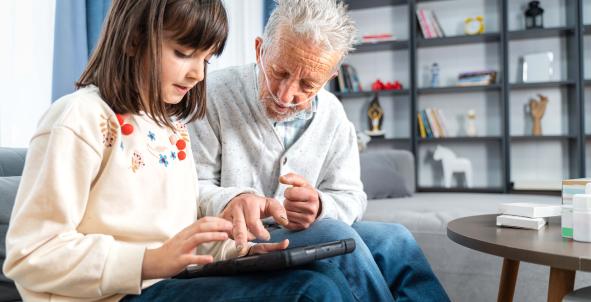 Digitale zorg: een oudere man met zuurstof en een kind kijken samen op een tablet