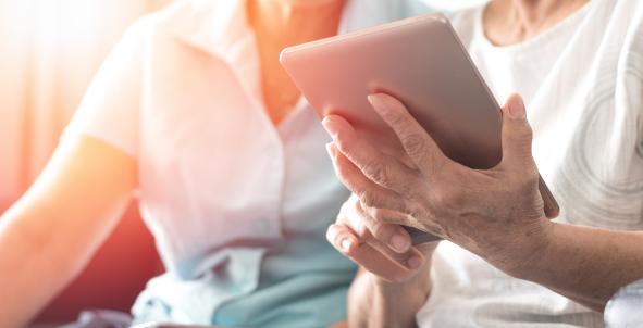 Foto van vrouw met tablet die hulp krijgt bij het gebruik ervan