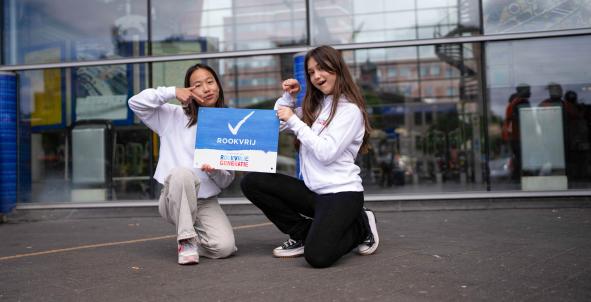 Meiden met rookvrij bordje in Amersfoort op stationsplein