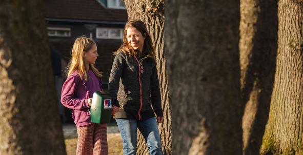 Moeder en dochter lopen met collectebus