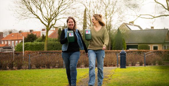 Twee vrouwen laten lachend de collectebus van Longfonds zien