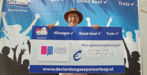 Man houdt lachend en trots een cheque voor Longfonds vast