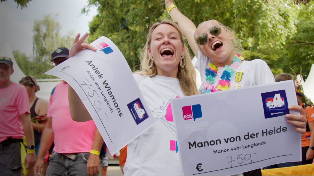 Twee jonge vrouwen lachen en juichen met een cheque in hun hand