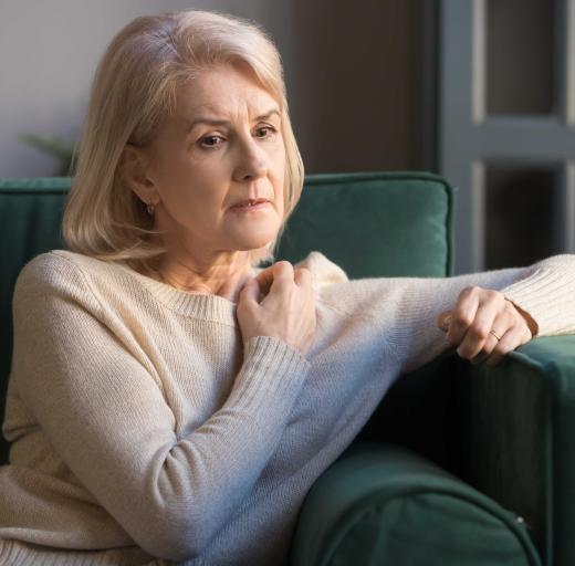 Vrouw zit op de bank, kijkt bezorgd