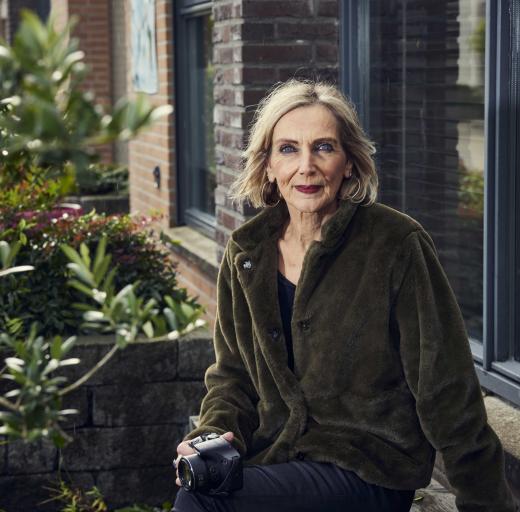 Jorien zit buiten voor een raam, met haar camera in haar hand