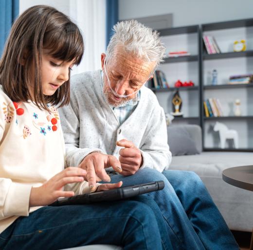 Digitale zorg: een oudere man met zuurstof en een kind kijken samen op een tablet