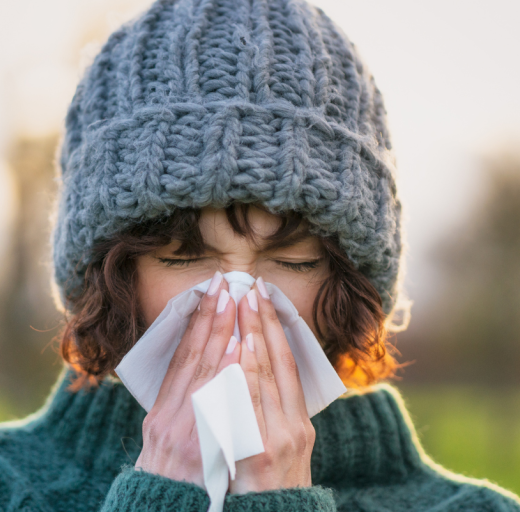 vrouw met muts niest of snuit haar neus