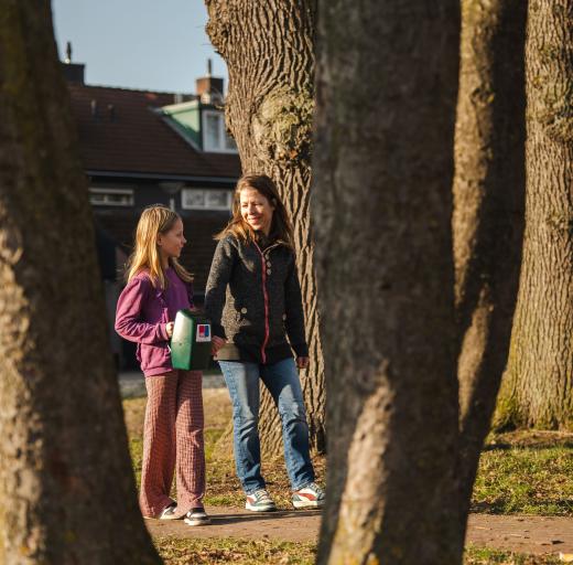 Moeder en dochter lopen met collectebus