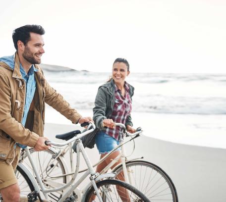 Stel lopend op het strand, fiets aan de hand