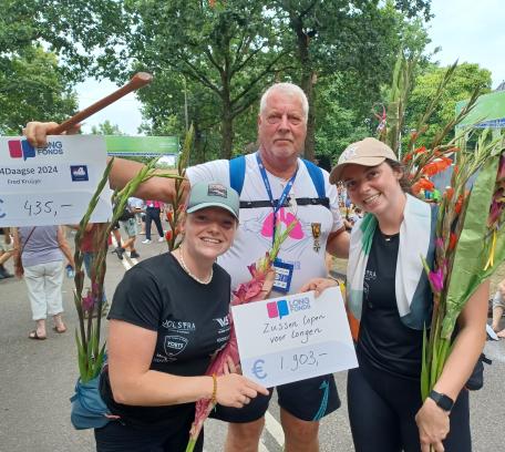Twee vrouwen en een man houden een cheque van Longfonds vast tijdens Nijmeegse Vierdaagse