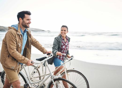 Stel lopend op het strand, fiets aan de hand