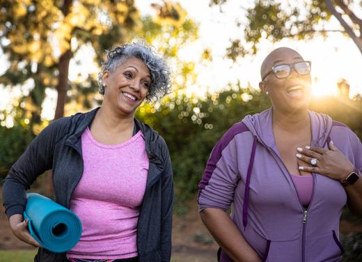 Twee vrouwen met yogamat staan buiten na het bewegen, ondergaande zon