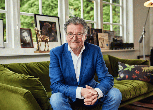 Edwin de Vries op de bank in zijn woonkamer, een Gouden Kalf op de achtergrond