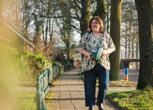 Annemieke loopt met collectebus door de straat